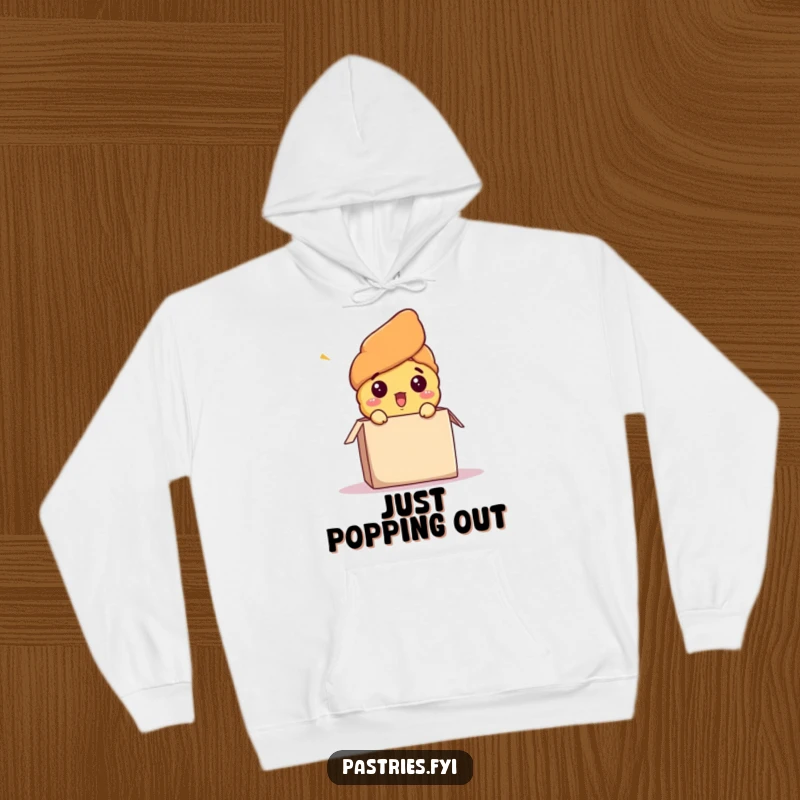 Funny hoodie featuring a shocked croissant character bursting energetically out of a cardboard box, a perfect warm and humorous gift.